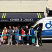 Group of people at a ribbon-cutting outside Henderson Chamber of Commerce, with a Deal Plumbing van in the background.