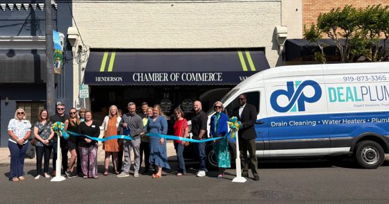 Group of people at a ribbon-cutting outside Henderson Chamber of Commerce, with a Deal Plumbing van in the background.
