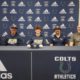 Young athlete signs an NIL deal at a press table flanked by coaches and family, with an Adidas backdrop and Colts Athletics branding behind them.